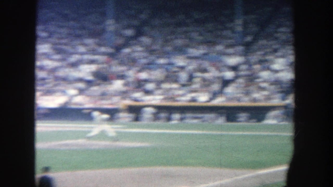 Pitcher on a baseball field with a packed grandstand behind him.