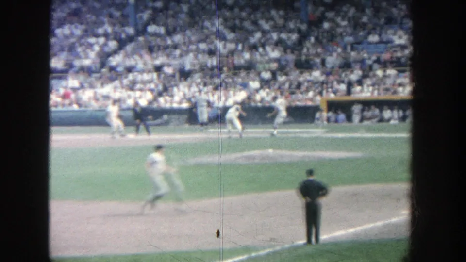 1964 Yankee Stadium home-movie frame with a runner heading up the baseline while an umpire watches near the infield.