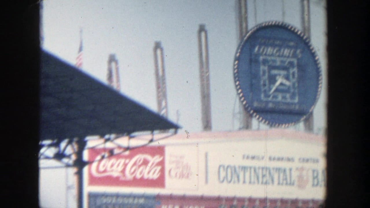 Yankee Stadium scoreboard area with Longines clock, Coca-Cola sign, roofline, and flagpoles.