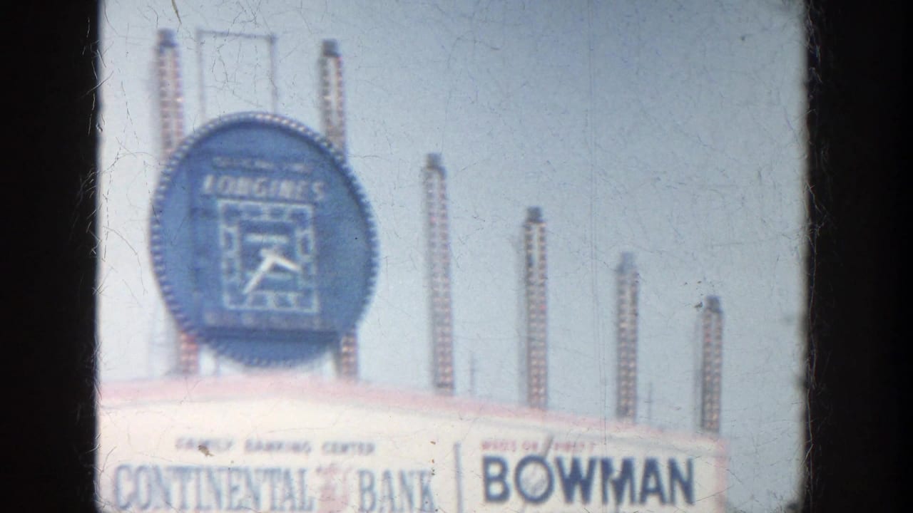 1964 Yankee Stadium scoreboard view with the Longines clock, Continental Bank lettering, Bowman sign, and vertical poles behind it.