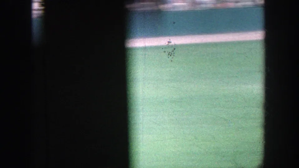 The handheld spectator view shifts across the Yankee Stadium field, leaving mostly grass, wall, and dark film-frame obstructions visible.