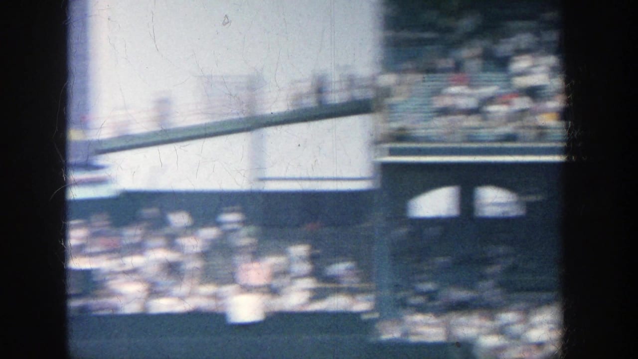 Motion-blurred 1964 Yankee Stadium view across spectators, railings, and stadium architecture with strong exposure changes.