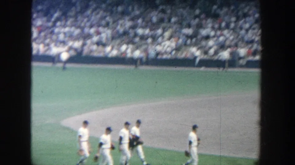 1964 Yankee Stadium view of players in white uniforms walking near the infield, filmed from a spectator position.