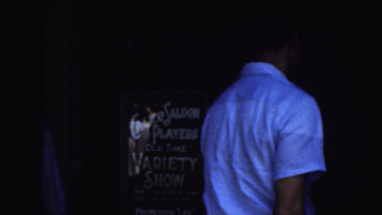 1952 California 8mm frame showing a man in a light shirt near a dark entrance and a Coco Saloon Players variety show sign.