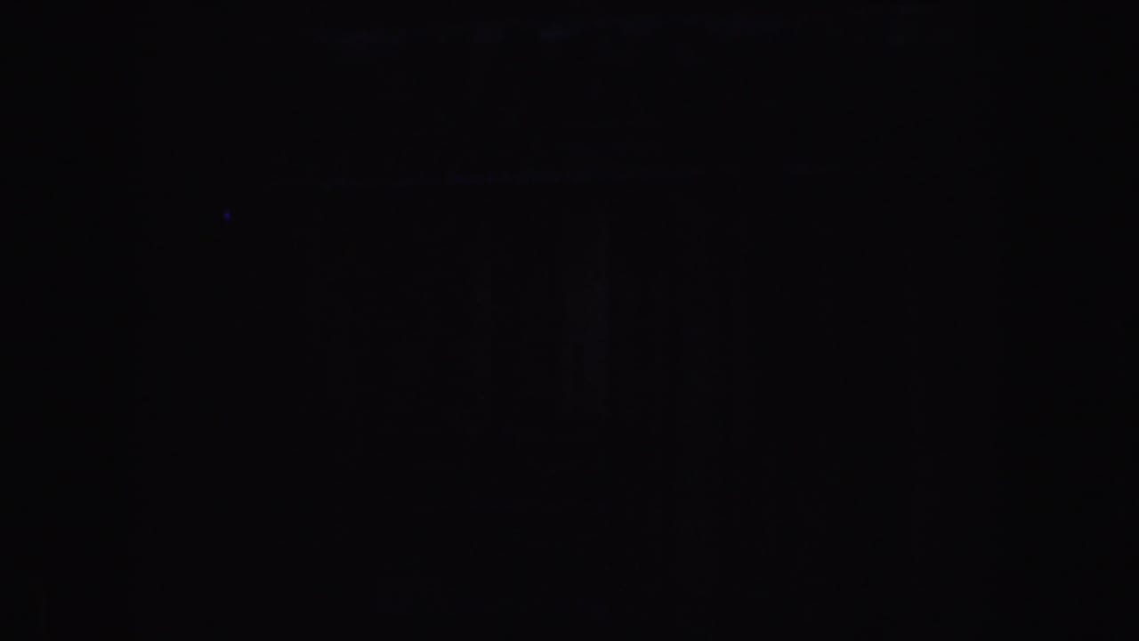 Very dark 1952 California 8mm frame with faint colored flares and indistinct indoor forms.