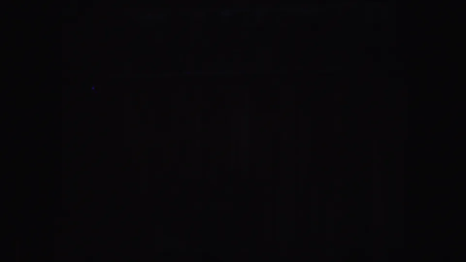 Very dark 1952 California 8mm frame with faint colored flares and indistinct indoor forms.