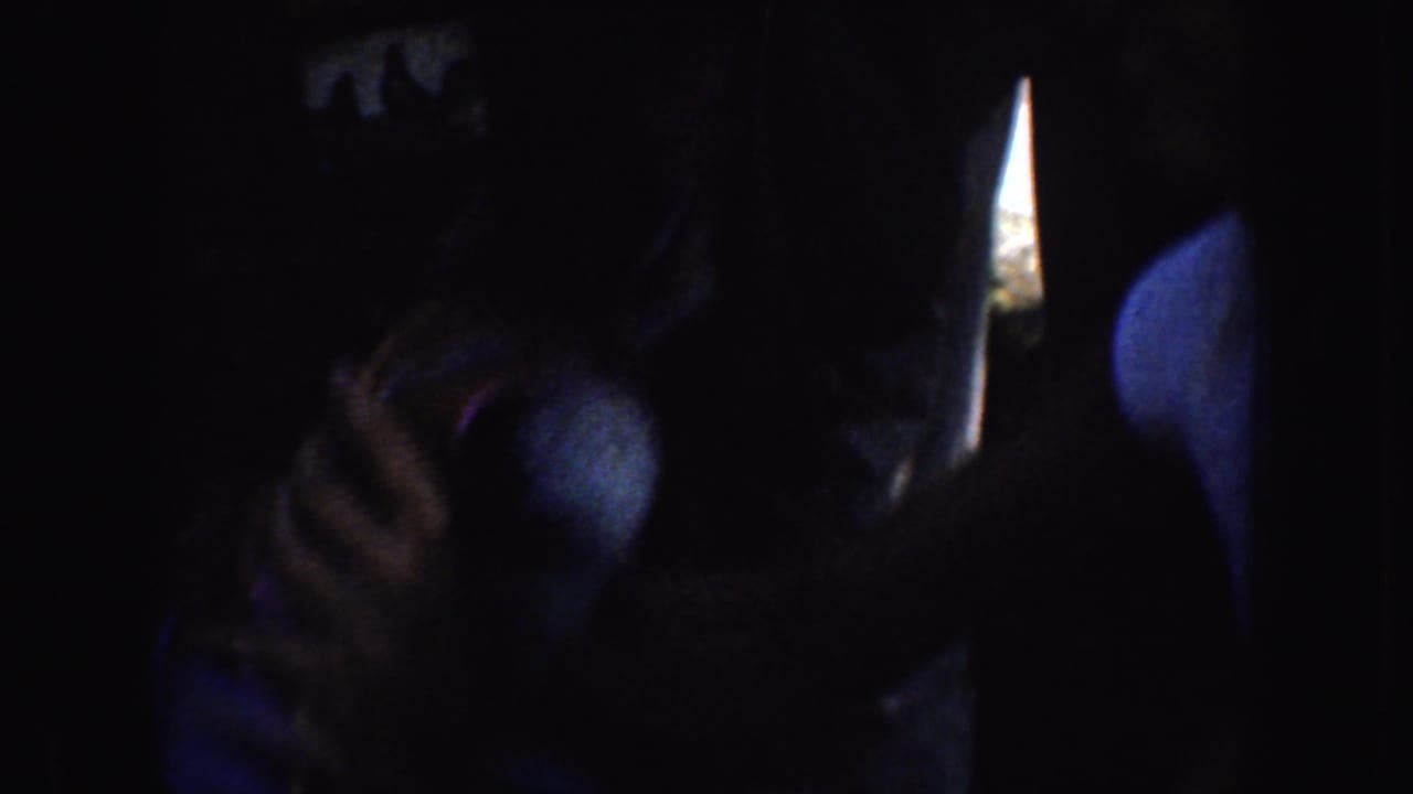 Close dark view of a woman looking down while holding a blue item near her lap.