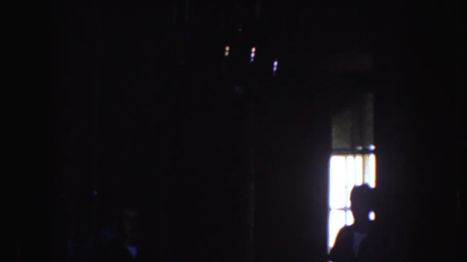 1952 California 8mm frame with the chandelier receding into darkness and a bright window-like opening near the lower right edge.