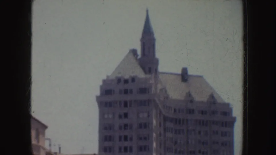 1952 California 8mm frame centered on the upper stories of a tall older building with a narrow tower-like feature.