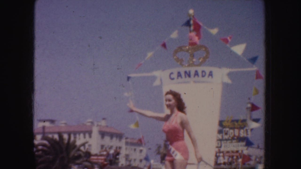 Woman in pink swimsuit waves beside a float marked Canada during a parade.
