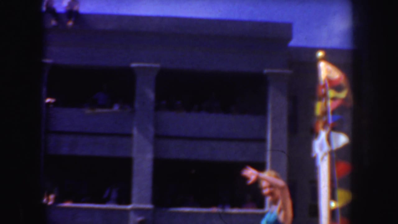 1952 California home-movie frame showing a white-uniformed man near a building, with strong color shift and dark film borders.