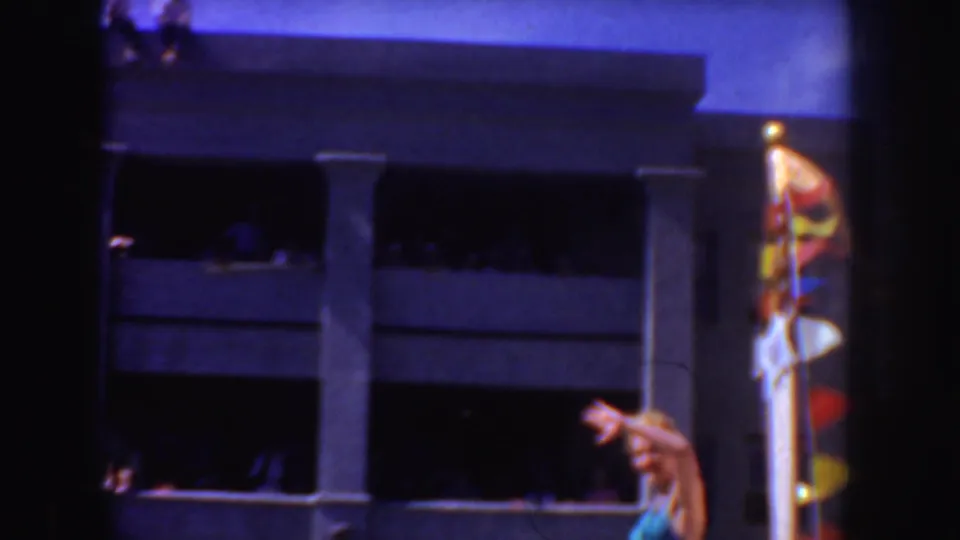 1952 California home-movie frame showing a white-uniformed man near a building, with strong color shift and dark film borders.