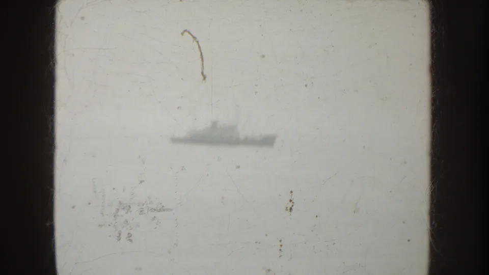 A distant gray vessel appears through haze on the water in this scratched 1952 California 8mm frame.