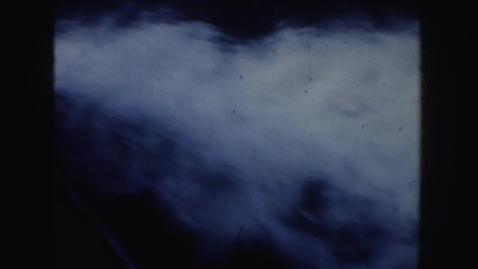Soft blue-white 8mm frame that appears to show water, wake, or sky, with dark borders and visible film wear.