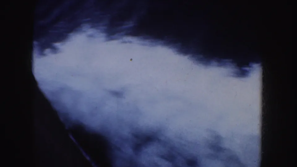 Soft 1952 8mm frame of blue-white shapes that may be ocean wake or sky, bordered by dark film edges.