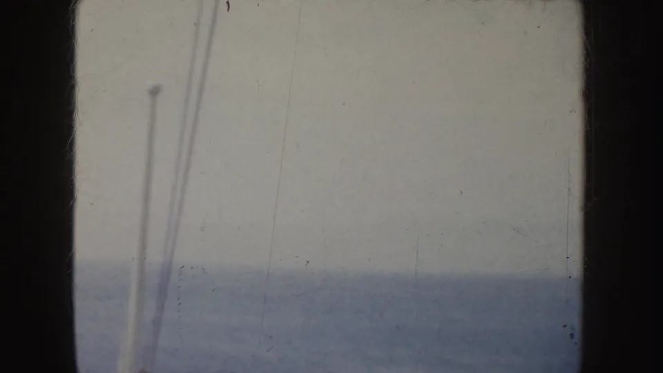 1952 California 8mm frame showing a hazy ocean horizon, overcast sky, and pale vertical rigging near the left edge.