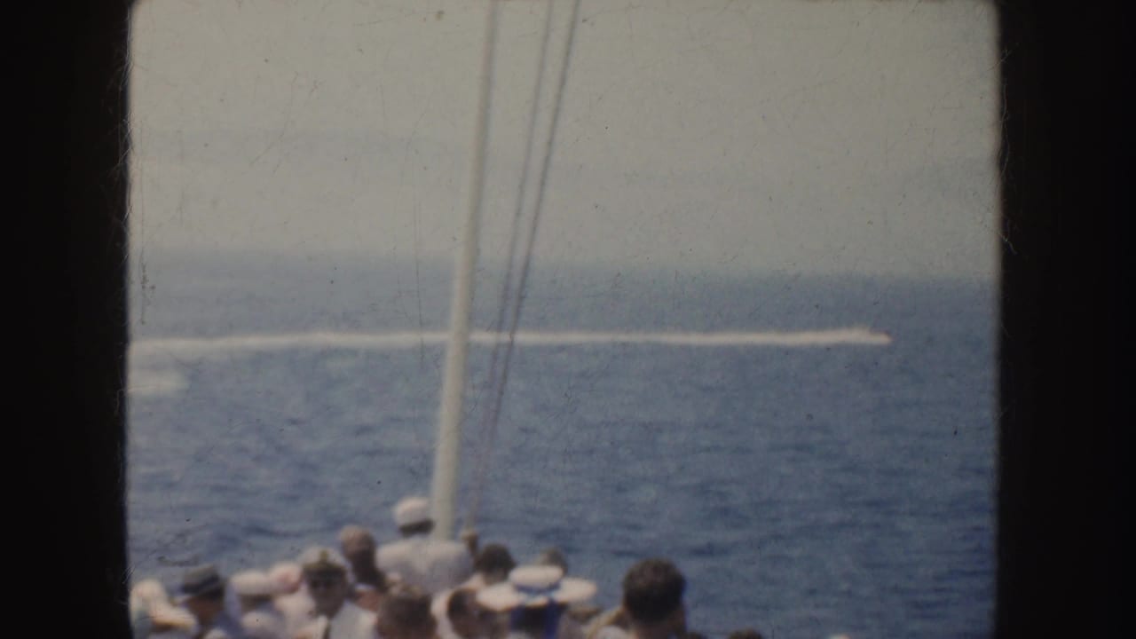 Passengers on a vessel watch a motorboat leaving a long wake across the sea.