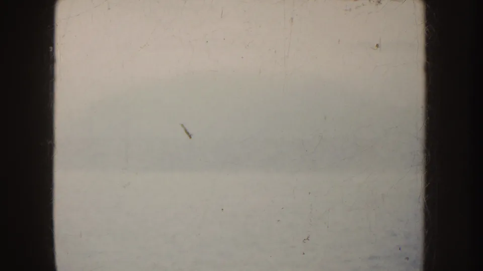 The final frame is largely overexposed pale background with film borders, dust, and scratches from the 8mm scan.