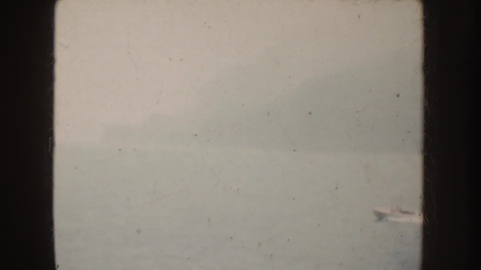 1952 California 8mm frame showing a fog-muted body of water, faint horizon detail, film scratches, and dark frame borders.