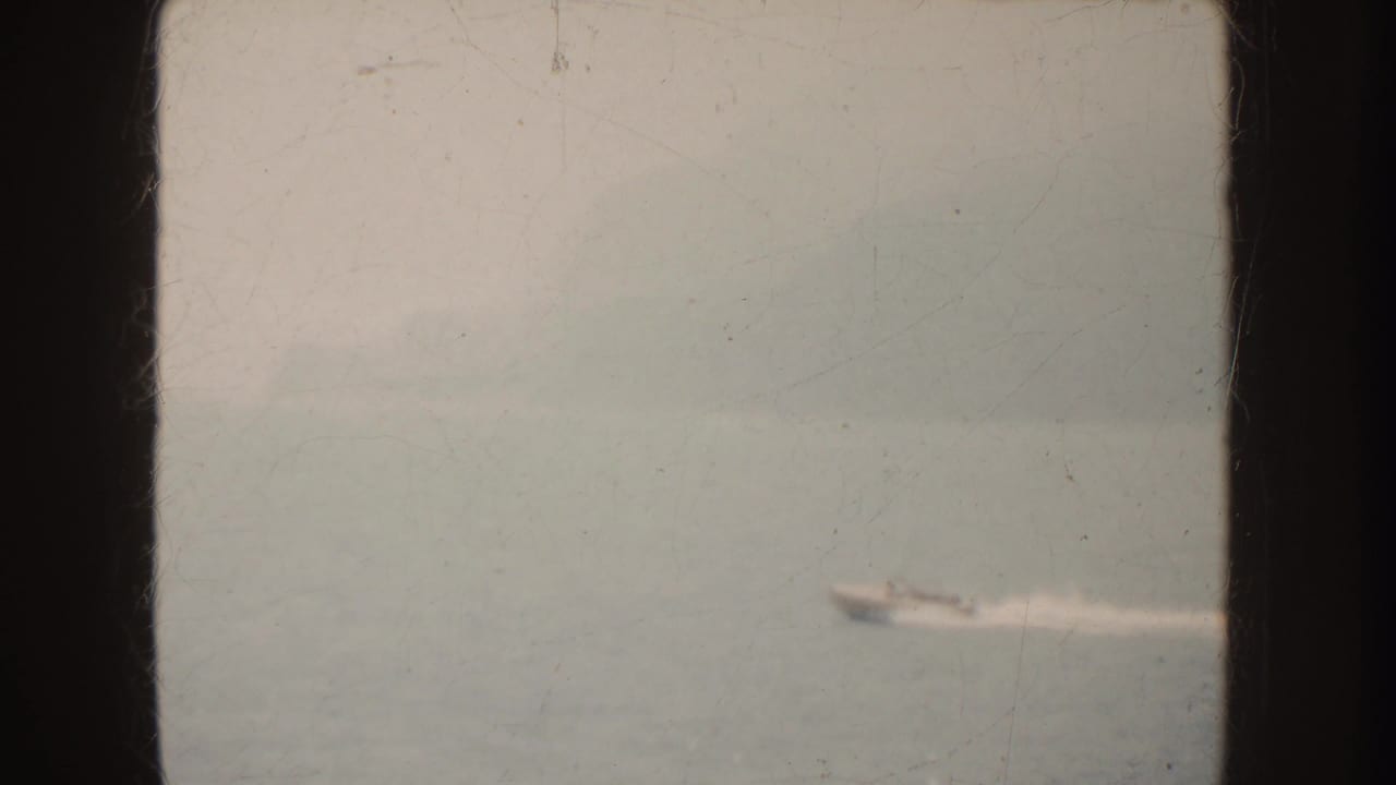 Distant speedboat moving across open water with a faint white wake.