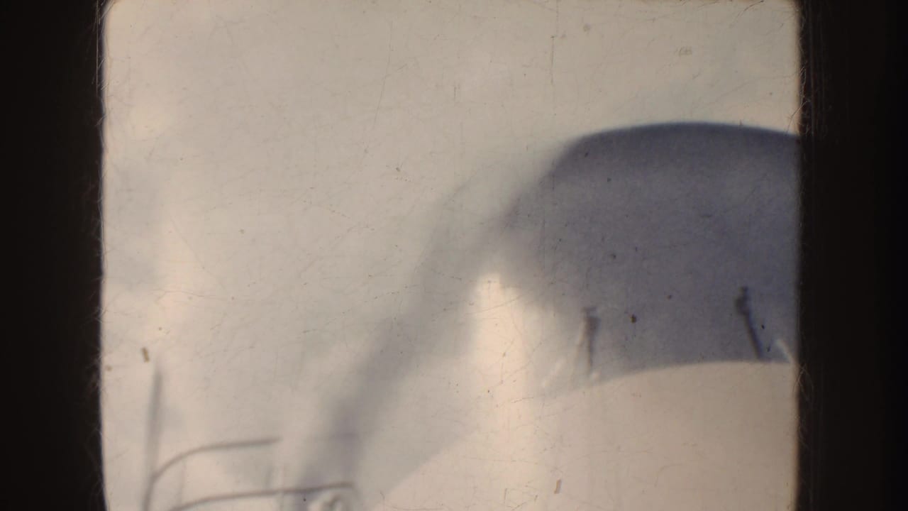 1952 California 8mm frame showing a rounded foreground structure seen through dark framing, with water and misty mountains beyond.