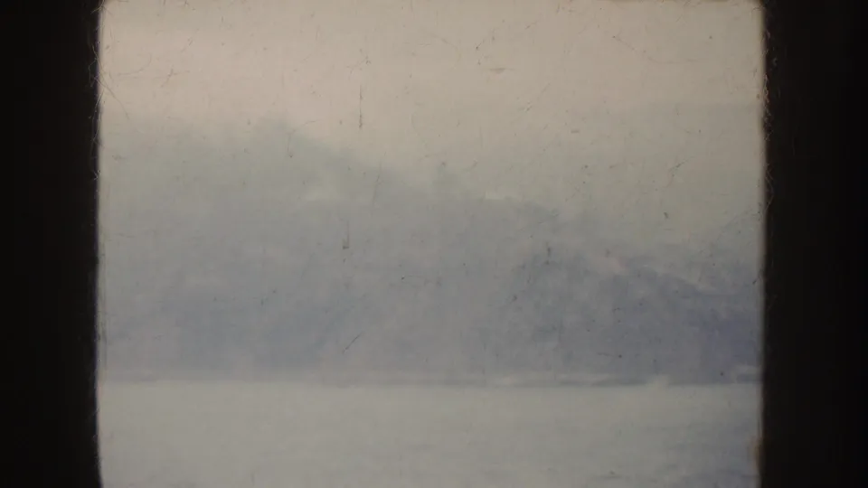 1952 California 8mm frame with a soft, misted view of water and distant mountains through dark vertical framing.