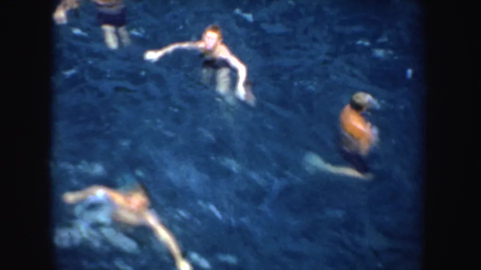 Elevated 1952 California home-movie view of swimmers in blue water, with soft focus and visible film-frame borders.