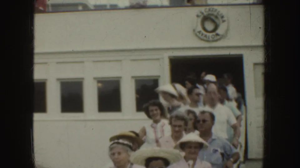 A crowd of visitors, many in hats, stands at a white doorway with partial Catalina Avalon signage visible above.