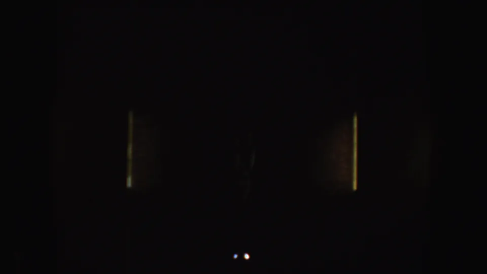 Dark 8mm home-movie frame with faint vertical light leaks and minimal scene detail visible.