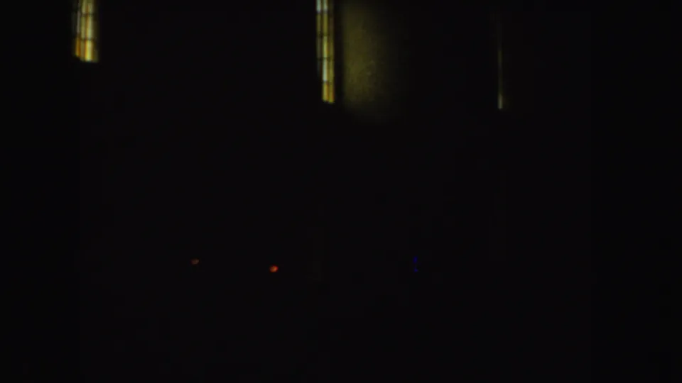 Dark opening frame from 1952 8mm footage, with small vertical window lights visible before the outdoor scene.