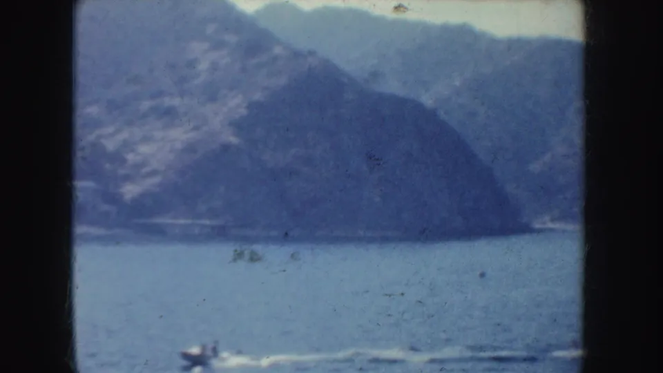 1952 California home-movie view from the water toward a hazy mountainous shoreline, with small-gauge film edges visible.