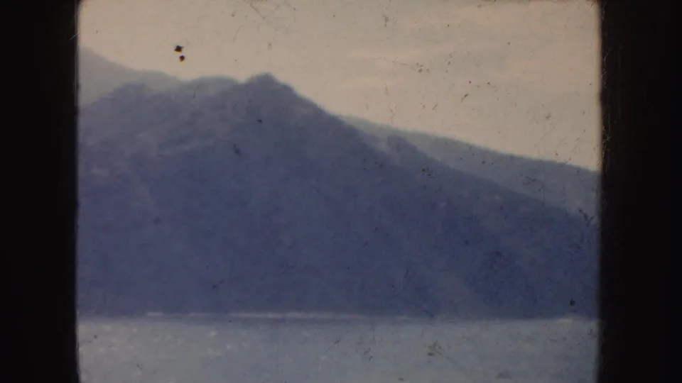 1952 California landscape frame with a distant mountain ridge, muted waterline, pale sky and aged 8mm surface marks.