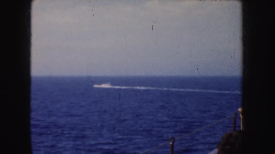 1952 California 8mm view over a boat rail toward a distant wake on the ocean, with cropped passengers partly visible near the lower right.