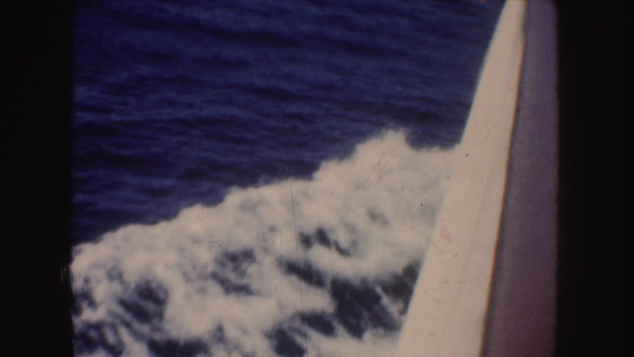 1952 California 8mm frame showing blue water and foamy wake passing beside the pale edge of a boat.
