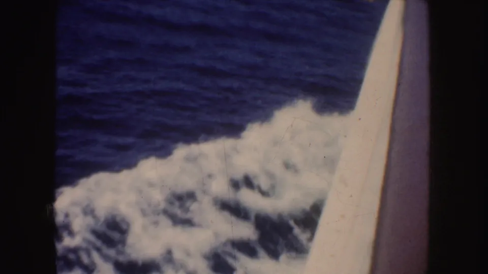 1952 California 8mm frame showing blue water and foamy wake passing beside the pale edge of a boat.