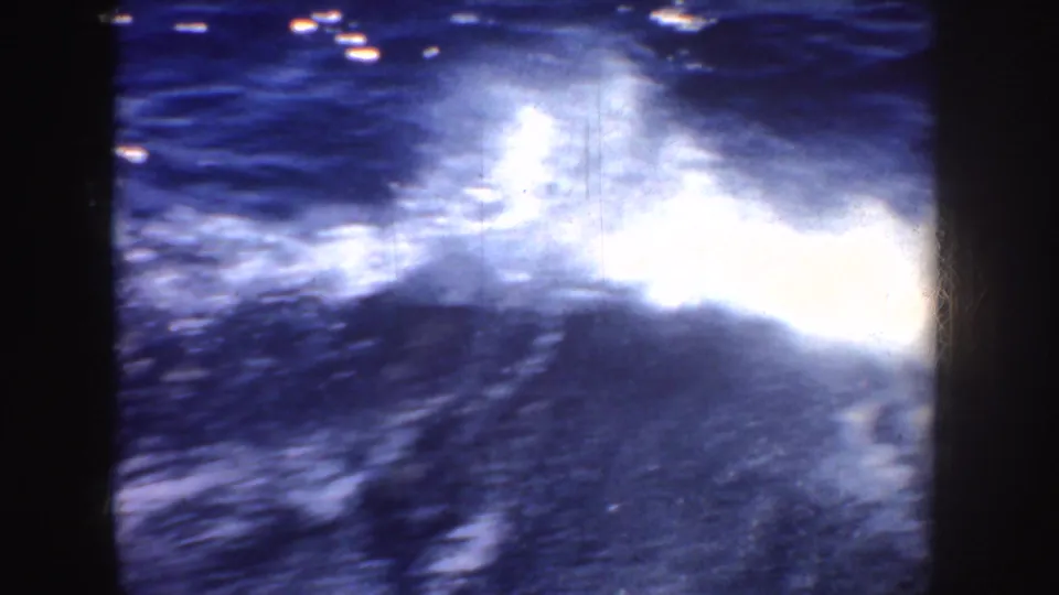 1952 California 8mm frame showing bright sun glare and white foam across dark blue water behind or beside the boat.