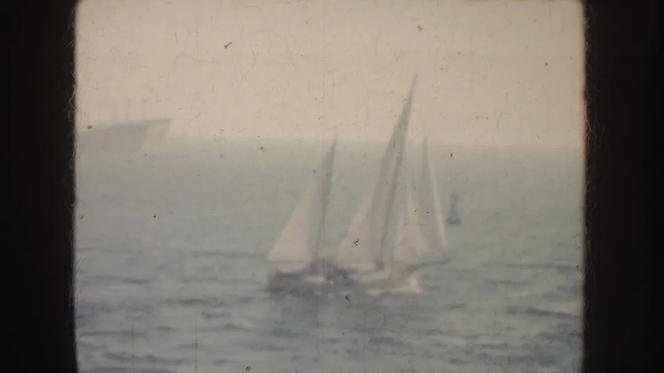 1952 California 8mm frame with several distant sailboats on calm water, viewed through dark framing.