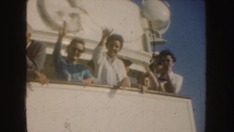 1952 California home-movie frame showing adults on a ship deck, some waving toward the camera against a bright sky.