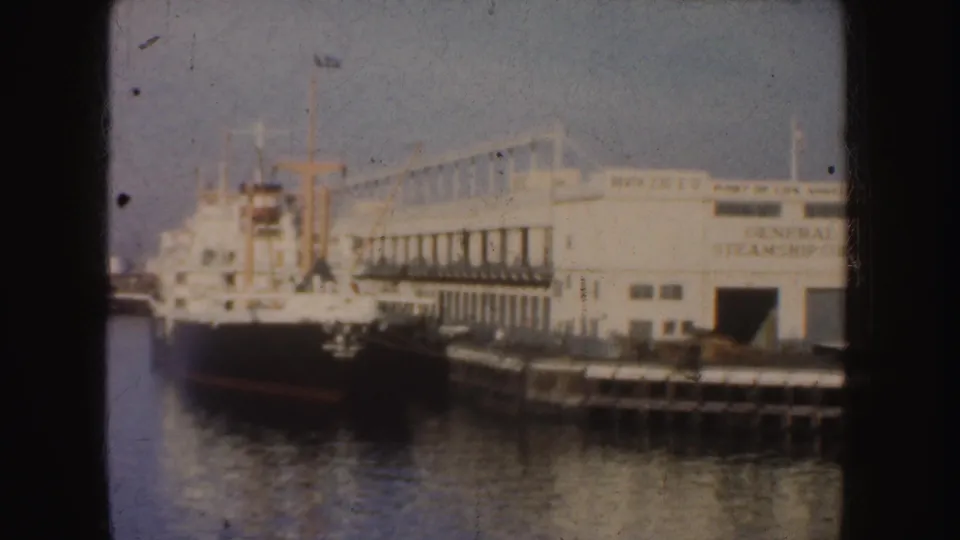 A docked black-and-white vessel sits beside a California pier building with General Steamship Co. signage.