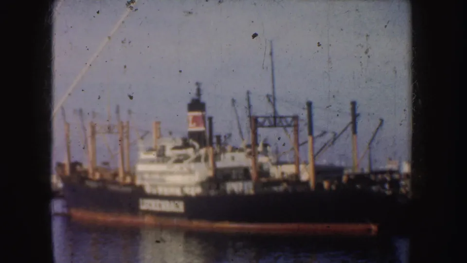 1952 California harbor view of a black Luckenbach cargo ship with a red-and-white funnel and port cranes in the background.