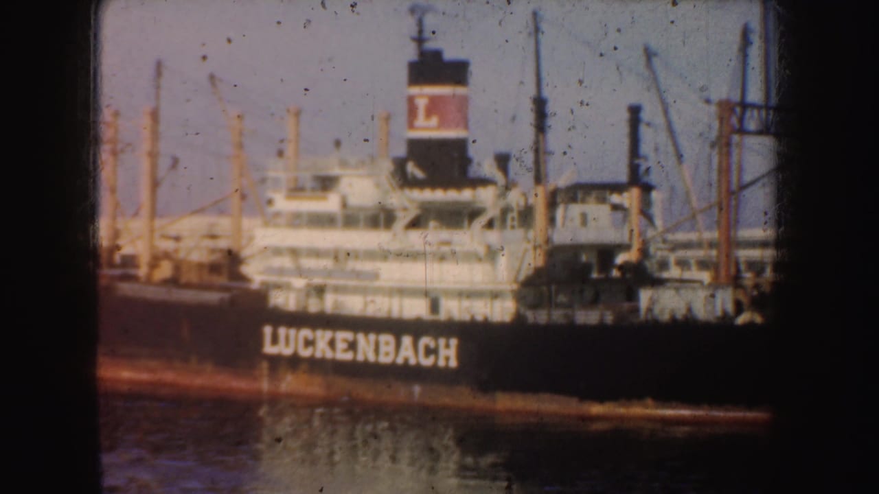 Closer view of the Luckenbach ship hull and funnel beside harbor cranes.