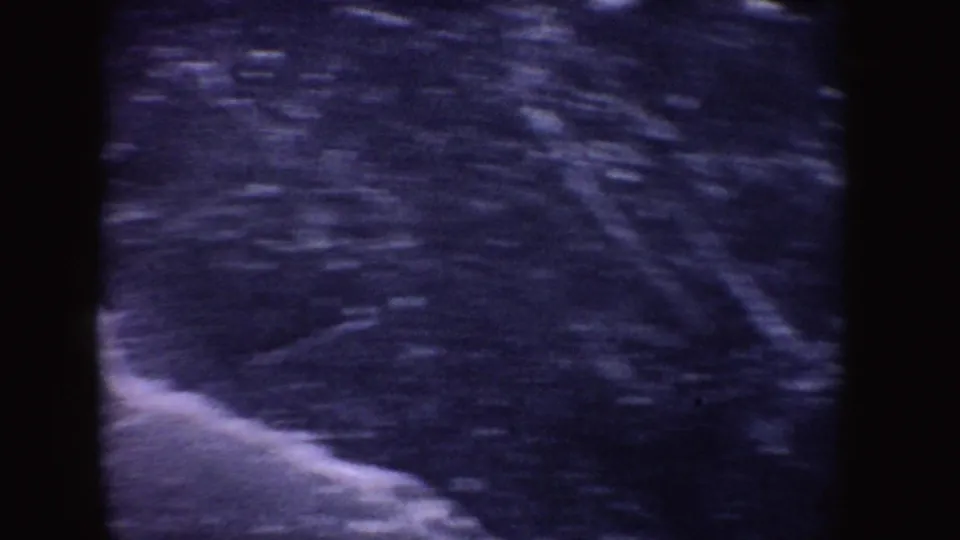1955 Idaho 8mm frame showing an icy outdoor surface in blue-purple color with soft focus and grain.