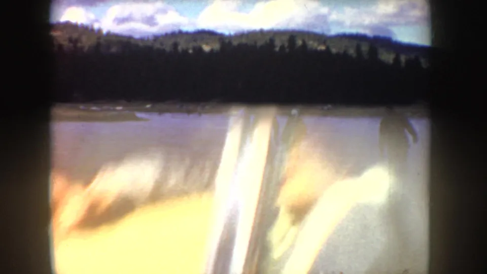 Blurred 1955 Idaho home-movie frame shifting from the frozen pond toward a bright car-window or vehicle interior view.