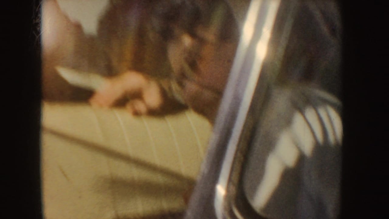 Passenger in a car interior holding a sandwich near cream upholstery.