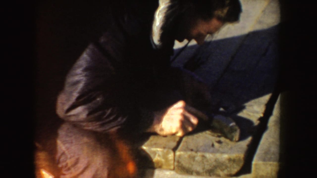 Close 8mm view of a man leaning over dock planks during a fish-cleaning sequence in Idaho, 1955.
