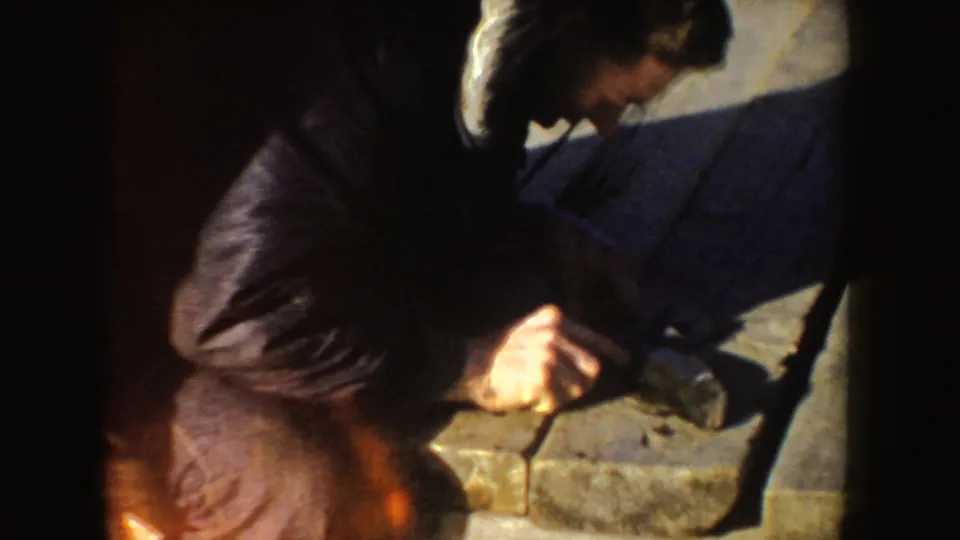 Close 8mm view of a man leaning over dock planks during a fish-cleaning sequence in Idaho, 1955.