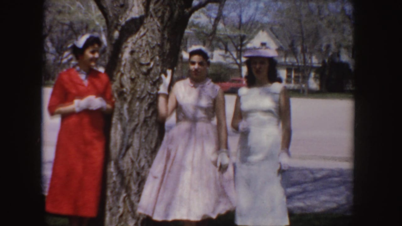 The women continue posing in their formal 1950s attire beside a large tree in a residential Idaho setting.