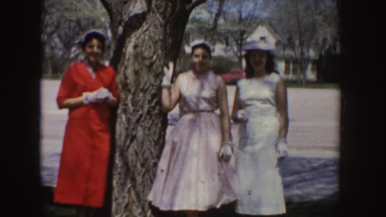The final 1955 Idaho frame shows three women smiling by a tree in formal dresses, with a street and houses behind them.
