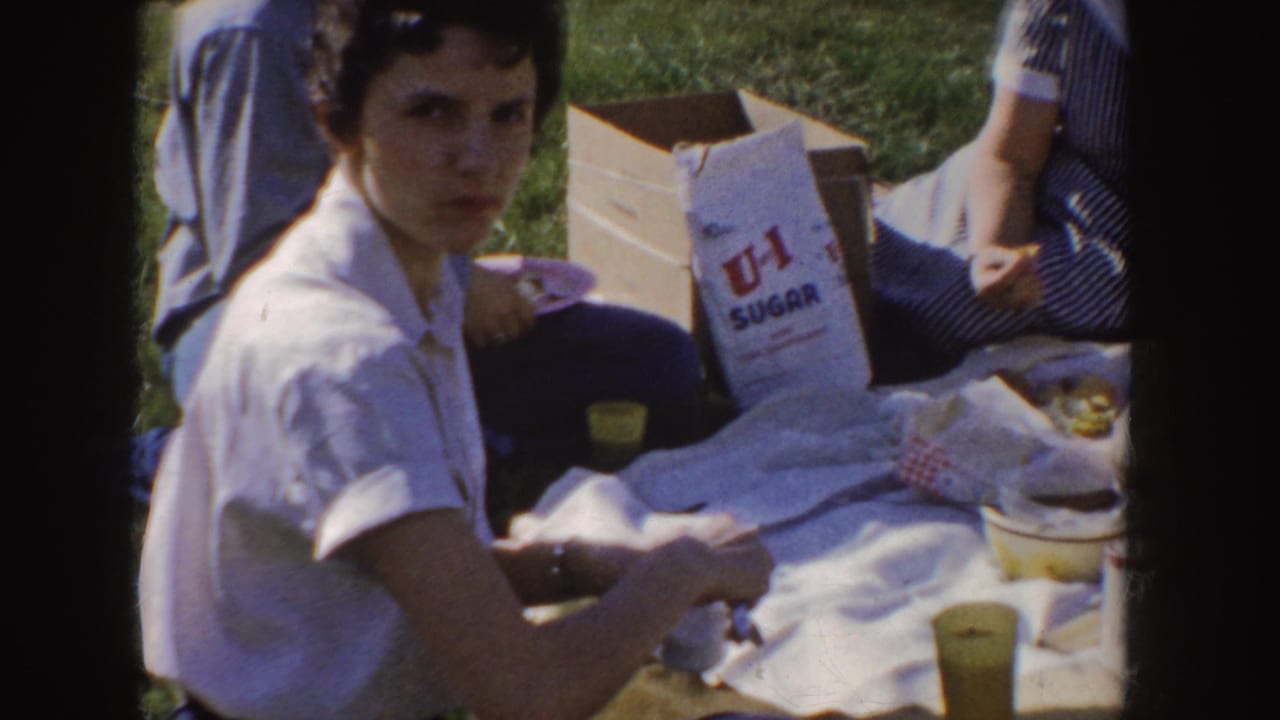 Young woman seated on a picnic blanket beside a U-I Sugar bag and yellow cups.