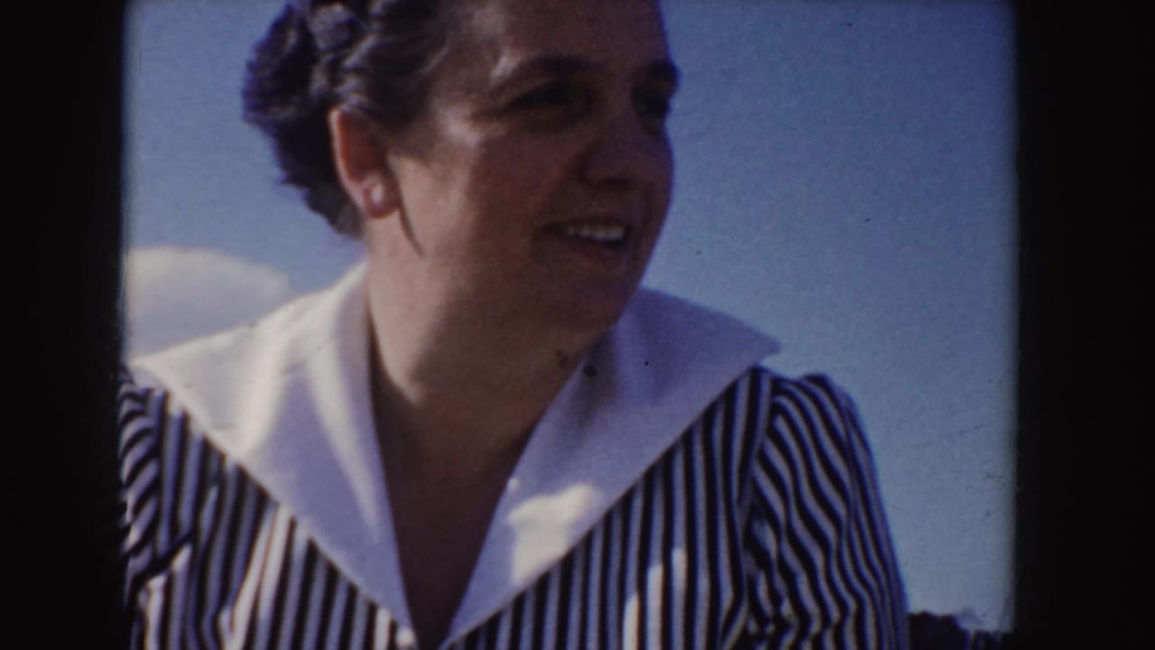Adult woman in a striped dress and white collar outdoors against blue sky.